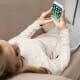 woman on couch using smartphone with ios apps on screen