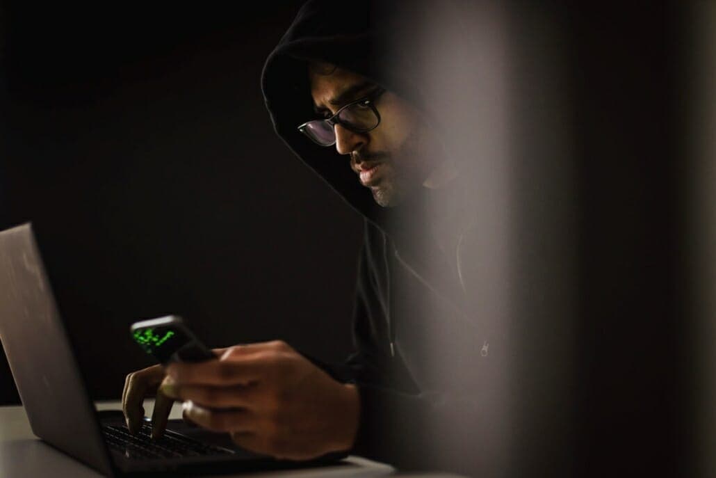Scammer hacking with SMISHING SMS text fraud using his laptop and phone