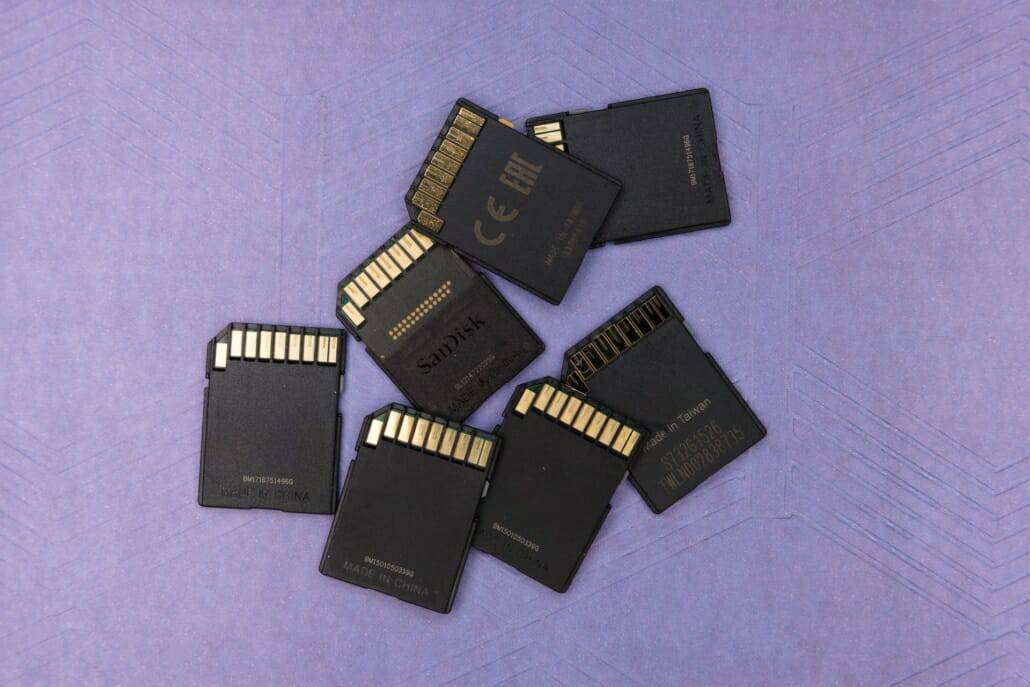 A pile of SD cards laid out on a purple surface representing file sharing and storage.