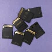 A pile of SD cards laid out on a purple surface representing file sharing and storage.