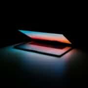 5 Cybersecurity Trends for 2023 Laptop sitting in the dark with the lid open slightly, illuminating the room with the screen for cybersecurity trends to come.