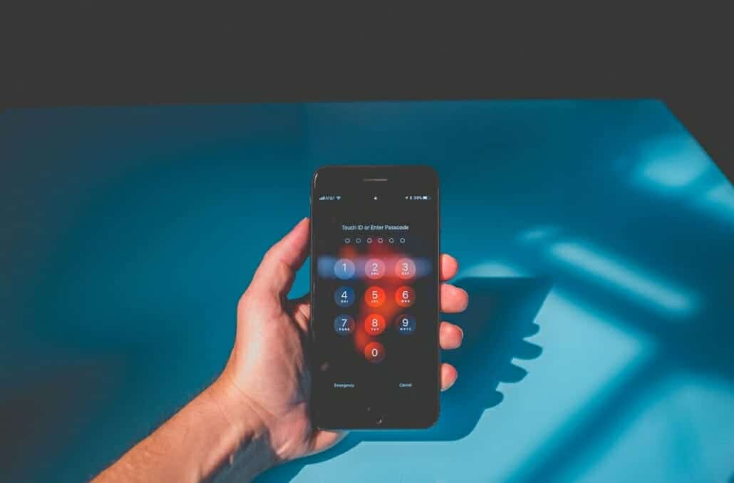 A person holding their iPhone with a passcode on it as a personal security measure to protect against things like hackers, ransomware and more.