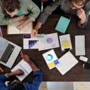 People huddled around an office table after an IT emergency wishing they had a preplan.