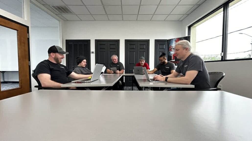 Bastionpoint Technology team collaborating around a conference table with laptops and tablets during a wireless survey planning session