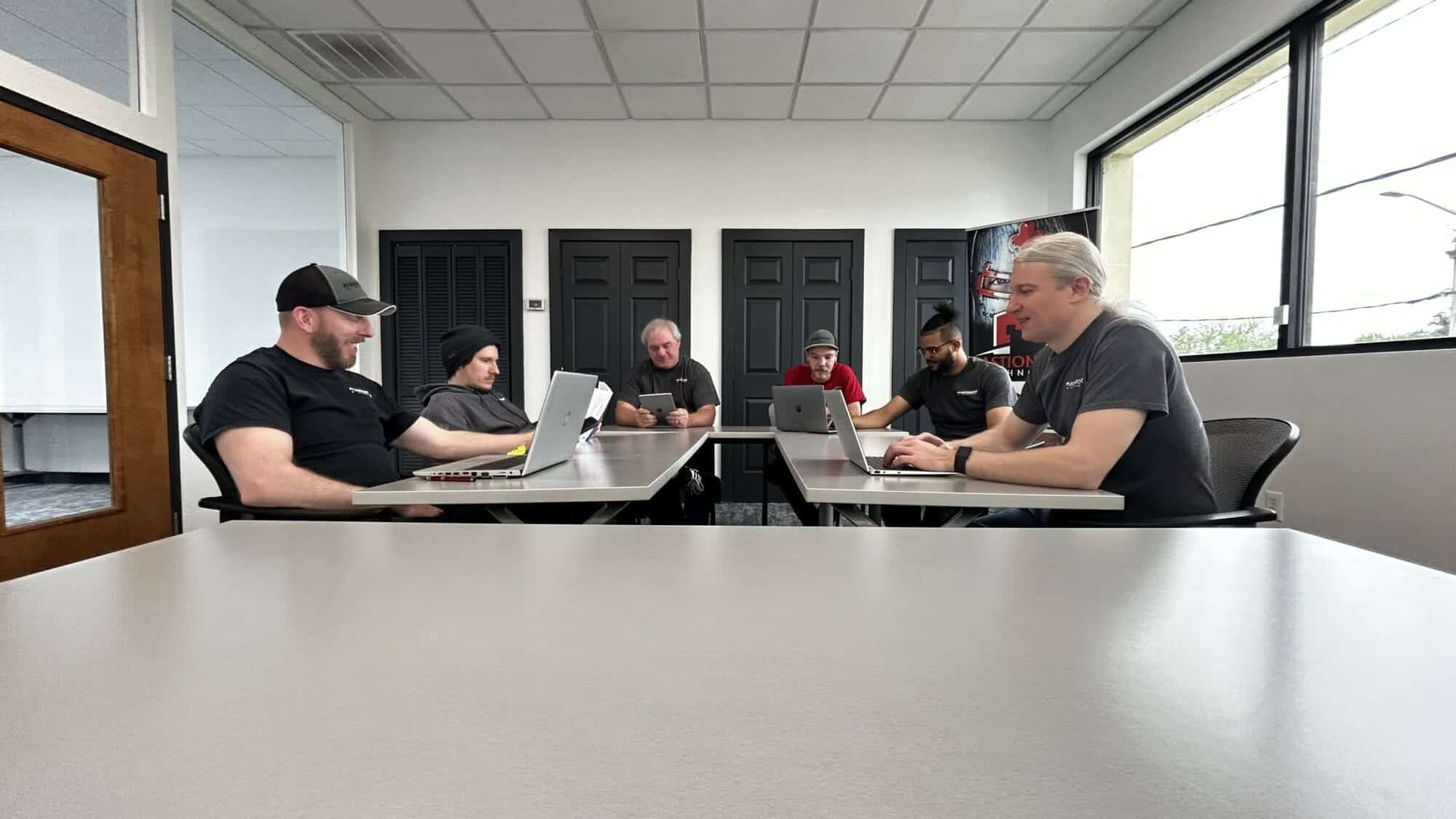 Bastionpoint Technology team collaborating around a conference table with laptops and tablets during a wireless survey planning session