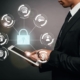 Man in suit holding tablet with infographic of lock, phone, key etc. IT management Concept
