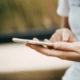Close-up of a person holding a smartphone and typing with one hand.