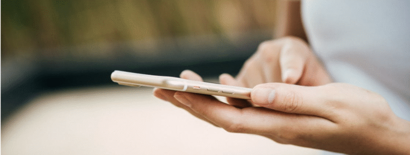Close-up of a person holding a smartphone and typing with one hand.