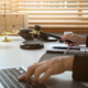 Judge holding a gavel while working on a laptop at her desk with scales of justice in the background