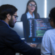 IT professionals collaborating at a workstation, reviewing code on dual monitors to troubleshoot issues and optimize system performance in a managed services environment.